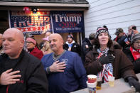 People put their hands over their hearts during the national anthem while watching a rally for President Donald Trump on a large screen television from a nearby bar in Wildwood, N.J., Tuesday, Jan. 28, 2020. (AP Photo/Seth Wenig)