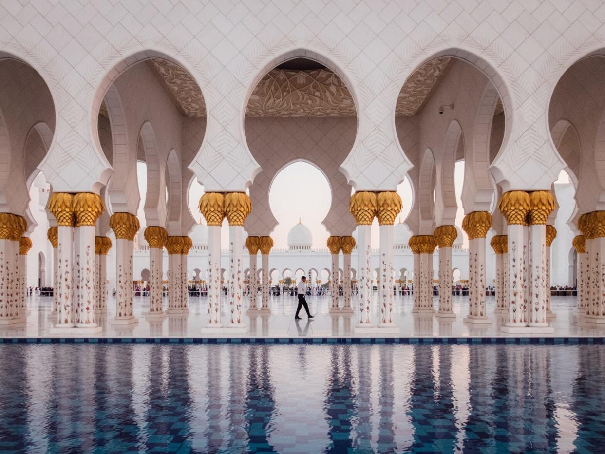 man walking through the Sheikh Zayed Grand Mosque in Abu Dhabi, United Arab Emirates