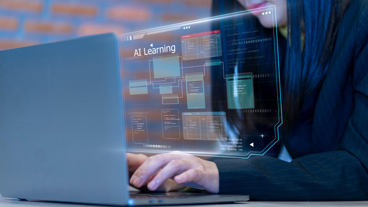  A person typing on a laptop with a virtual display in front of them with the text "AI Learning" above a series of windows. 