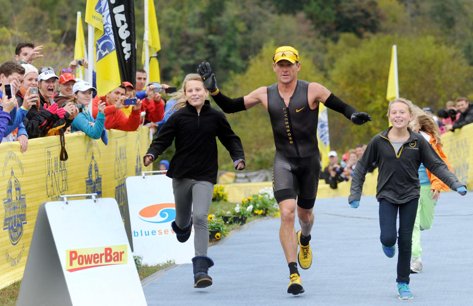 Lance Armstrong crosses the finish line of the Rev3 Half Full Triathalon with his ten-year-old twin daughters Grace, left, and Isabelle, right, Sunday, Oct. 7, 2012 in Ellicott City, Md. Armstrong joined other cancer survivors in the event which raised funds for the Ulman Cancer Fund for Young Adults. 