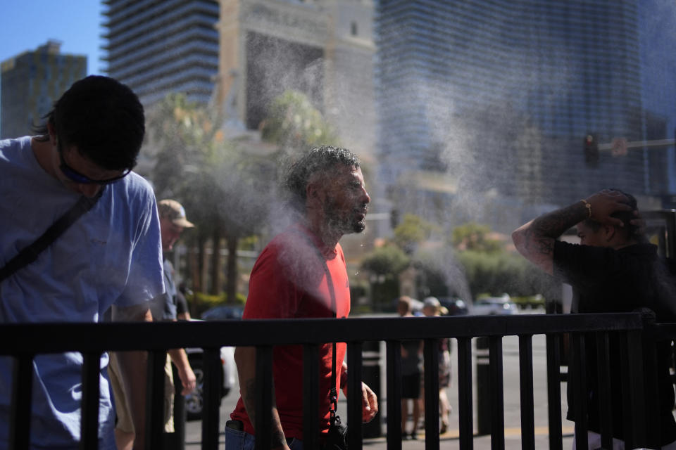 People cool off in misters along the Las Vegas Strip, Sunday, July 7, 2024, in Las Vegas. A heat wave is spreading across the Western U.S., the National Weather Service said, sending many residents in search of a cool haven from the dangerously high temperatures. (AP Photo/John Locher)