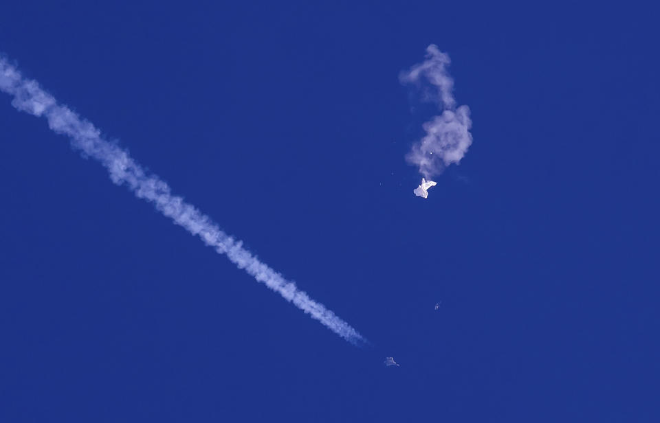 FILE - A fighter jet flies past the remnants of a large balloon after it was shot down above the Atlantic Ocean, just off the coast of South Carolina near Myrtle Beach on Feb. 4, 2023. (Chad Fish via AP, File)