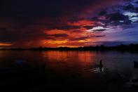 <p>Ein Mann im brasilianischen Pantanal schreitet während eines atemberaubenden Sonnenuntergangs durch einen See. (Bild: CARL DE SOUZA/AFP/Getty Images) </p>