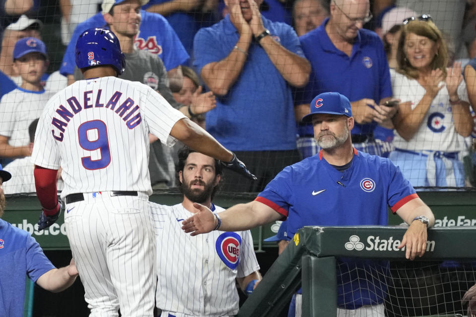 Chicago Cubs' Jeimer Candelario (9) is greeted at the dugout by manager David Ross, right, and Dansby Swanson, after Candelario scored on Nick Madrigal's double off Cincinnati Reds starting pitcher Ben Lively during the fourth inning of a baseball game, Tuesday, Aug. 1, 2023, in Chicago. (AP Photo/Charles Rex Arbogast)