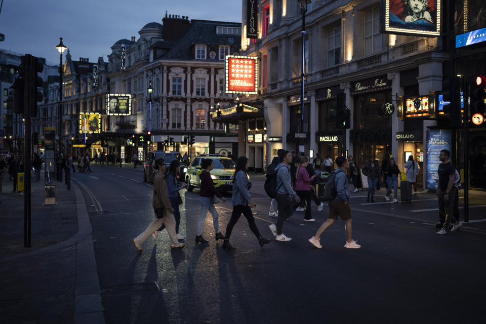 People cross Shaftesbury Avenue in London, Sunday, Sept. 11, 2022. On morning television, the moment was singularly somber — the departure of the hearse bearing the flag-draped coffin of Queen Elizabeth II. But at the very same hour, as fans in shorts and Ray-Bans streamed into London's Oval stadium for a long-anticipated cricket match, you wouldn't have guessed the country was preparing for the most royal of funerals. (AP Photo/Felipe Dana)