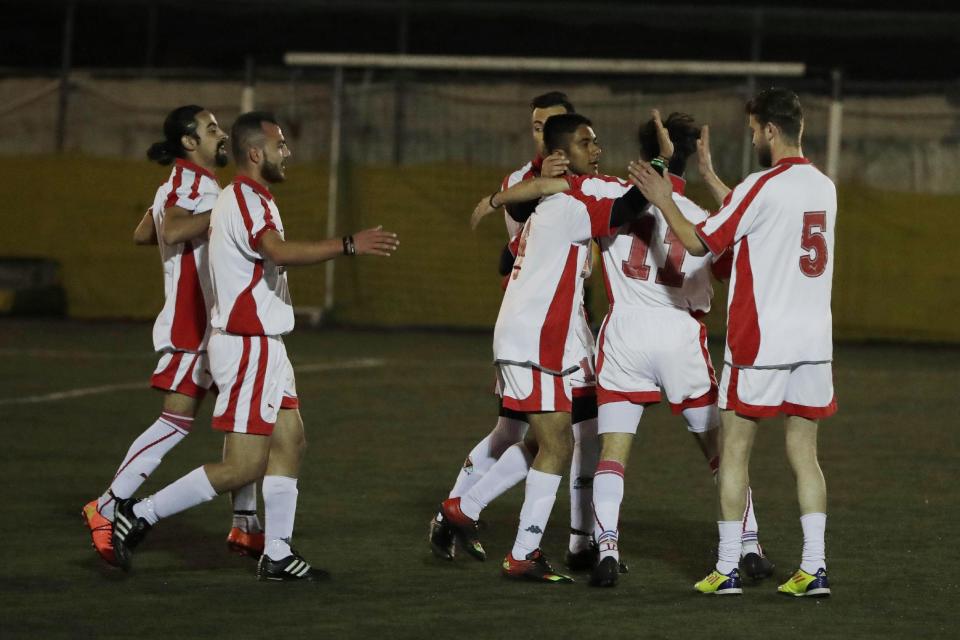 In this photo dated Sunday, Feb. 5, 2017, players of Hope Refugee Football Club celebrate a goal during a soccer match in western Athens. Former Greek national soccer team goalkeeper Antonis Nikopolidis, who became a national hero in 2004 during the European Cup, is heading a project to help refugees stranded in Greece regain a sense of purpose, working as a team. On weekends they play in an amateur league against teams made up of professional groups like lawyers, telecom workers, and accountants. (AP Photo/Thanassis Stavrakis)