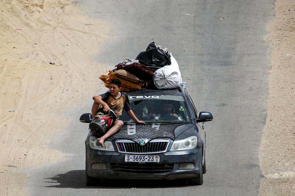 A boy sits on the hood of a vehicle loaded with belongings as members of a Palestinian family flee bound for Khan Yunis (AFP via Getty Images)