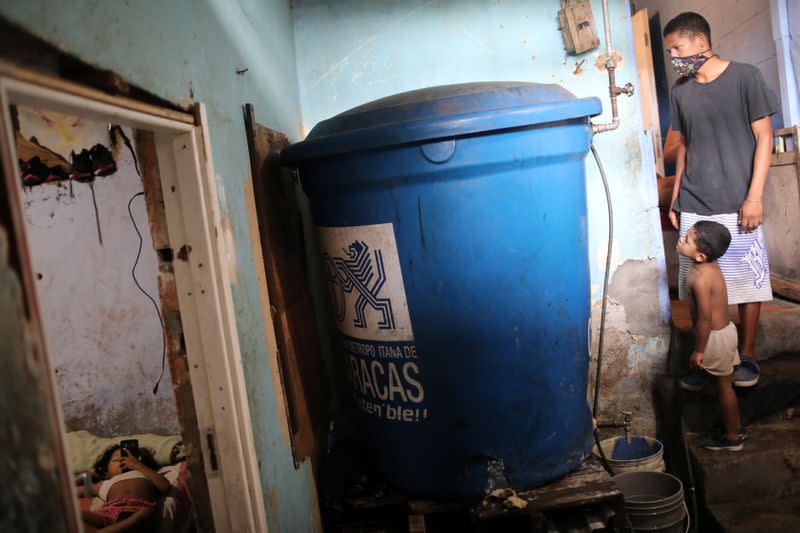 Inside his house, Henry checks the water level of his plastic tank, filled with water by a community-made pipe system that extract water that accumulated at a stalled tunnel construction project near El Avila mountain that borders the city of Caracas