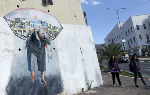 Schoolgirls walk past a mural in the Arab-Israeli town of Umm al-Fahm north of Tel Aviv