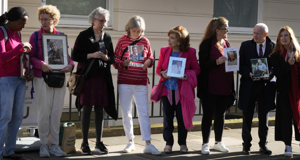 Bereaved families hold pictures of their loved ones as they stand outside the opening hearing of Module 2 of the UK Covid 19 Inquiry, in London, Tuesday, Oct. 3, 2023. Bereaved families are coming together to protest the fact that in the module investigating core government decision making during the pandemic, only 1 bereaved family witness has been called to give evidence, out of the over 230,115 families bereaved by Covid 19. (AP Photo/Kirsty Wigglesworth)