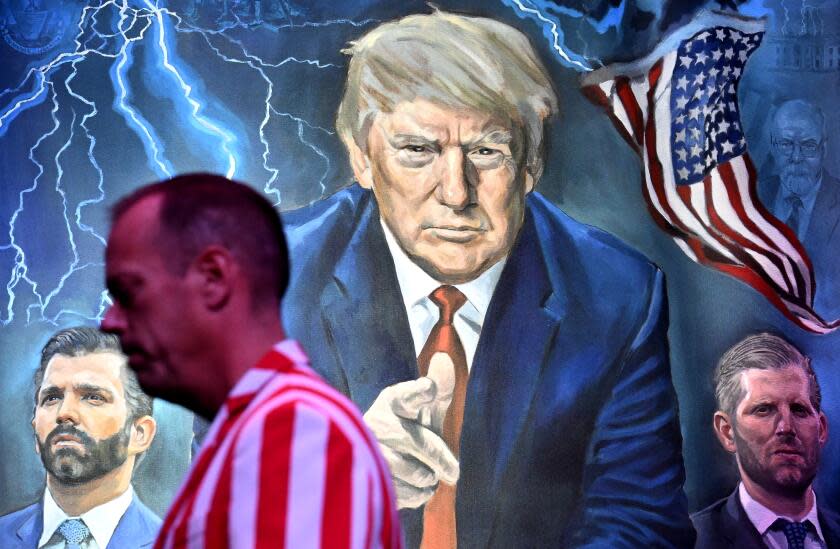 Las Vegas, Nevada August 24, 2023-A stage crew member walks by a poster of former President Donald Trump and his two sons Don Jr. and Eric during the ReAwaken Tour in Las Vegas. Some of the most influential American conservatives spoke during the two day event. (Wally Skalij/Los Angeles Times)