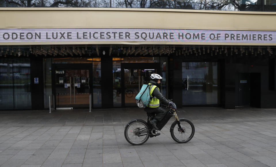 A cyclist rides past the flagship Odeon cinema in Leicester Square, in London, Tuesday, April 20, 2021. The coronavirus pandemic has devastated British theater, a world-renowned cultural export and major economic force. The theaters in London's West End shut when lockdown began in March 2020, and have remained closed for most of the past 13 months. Now they are preparing, with hope and apprehension, to welcome audiences back. (AP Photo/Alastair Grant)