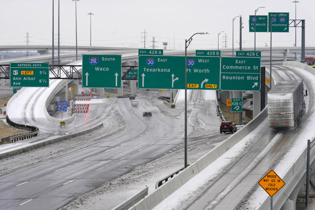 A road sign in yellow warns drivers of icy road conditions at a busy IH 30 and IH 35 interchange, Wednesday, Feb. 1, 2023, in Dallas. (AP Photo/Tony Gutierrez)