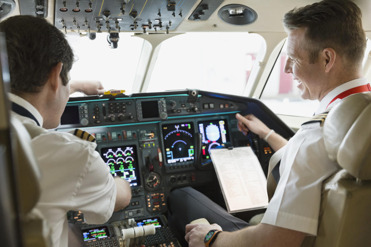 Male pilot and co-pilot checking instrument panel in airplane cockpit. Getty Images