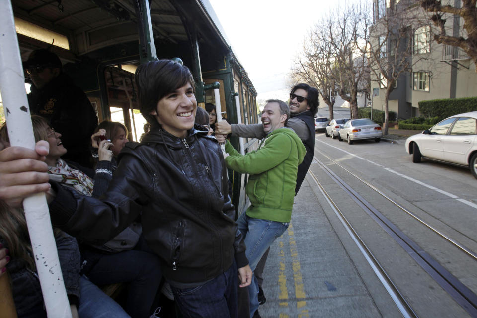 FILE - In this file photo from Jan. 21, 2011, from left, Franco Garavanno, Gustavo Ferrari and German Garavanno, who are visiting from Buenos Aires, ride a cable car up Hyde Street in San Francisco. In this city of innumerable tourist attractions, the clanging cable cars stand out as a top draw. They also stand out for the inordinate number of accidents and the millions of dollars annually the city pays out to settle lawsuits for broken bones, severed feet and bad bruises caused when 19th Century technology runs headlong into 21st Century city traffic and congestion. Recently, five passengers and two workers were injured after an inch-long bolt in the track caused their cable car to slam to a sudden stop. (AP Photo/Marcio Jose Sanchez)