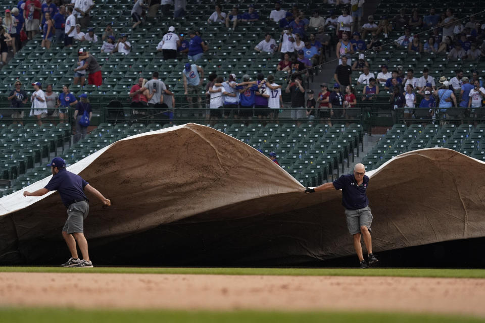 The grounds crew cover the field with a tarp during a rain delay in the ninth inning of a baseball game between the Arizona Diamondbacks and the Chicago Cubs in Chicago, Saturday, July 24, 2021. (AP Photo/Nam Y. Huh)