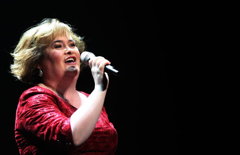 Susan Boyle tilts her head back while singing into a microphone