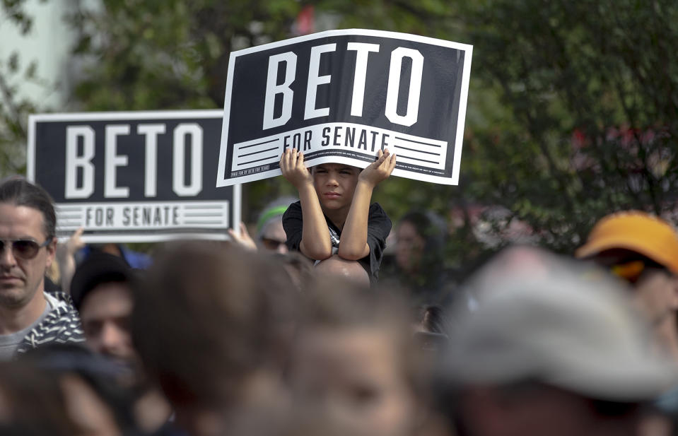 A boy uses a Beto for Senate sign to shade himself from the sun during a rally at the Pan American Neighborhood Park in Austin, Texas, on Sunday, Nov. 4, 2018. (Nick Wagner/Austin American-Statesman via AP)