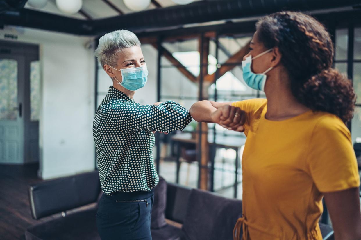 Two businesswomen greeting with elbows