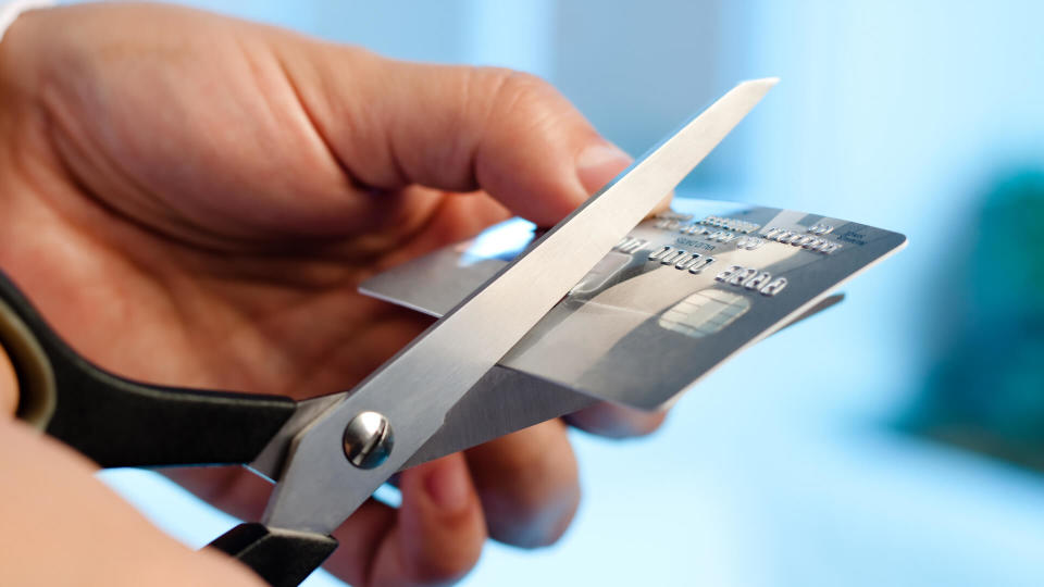 Scissors cutting a credit card on blue background.