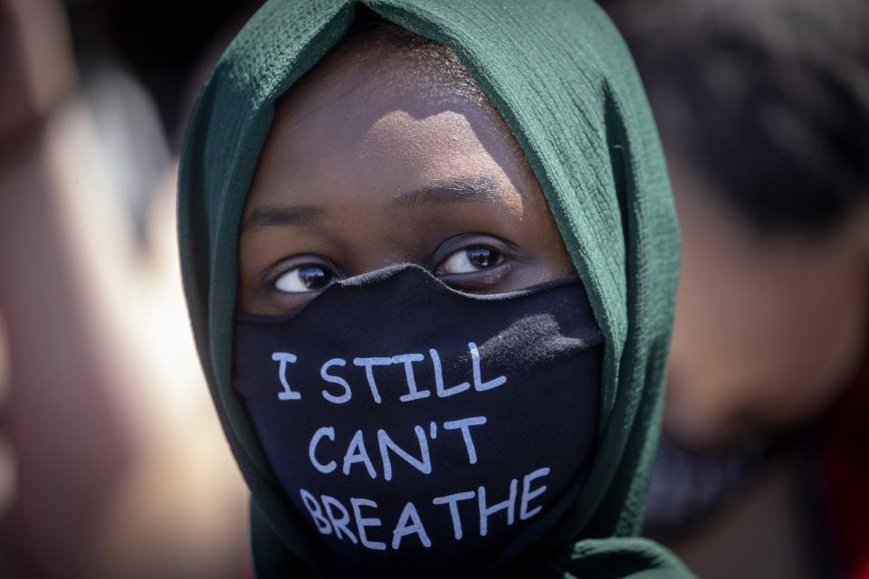 A person wears a mask at the Minneapolis corner where a police officer knelt on George Floyd's neck.