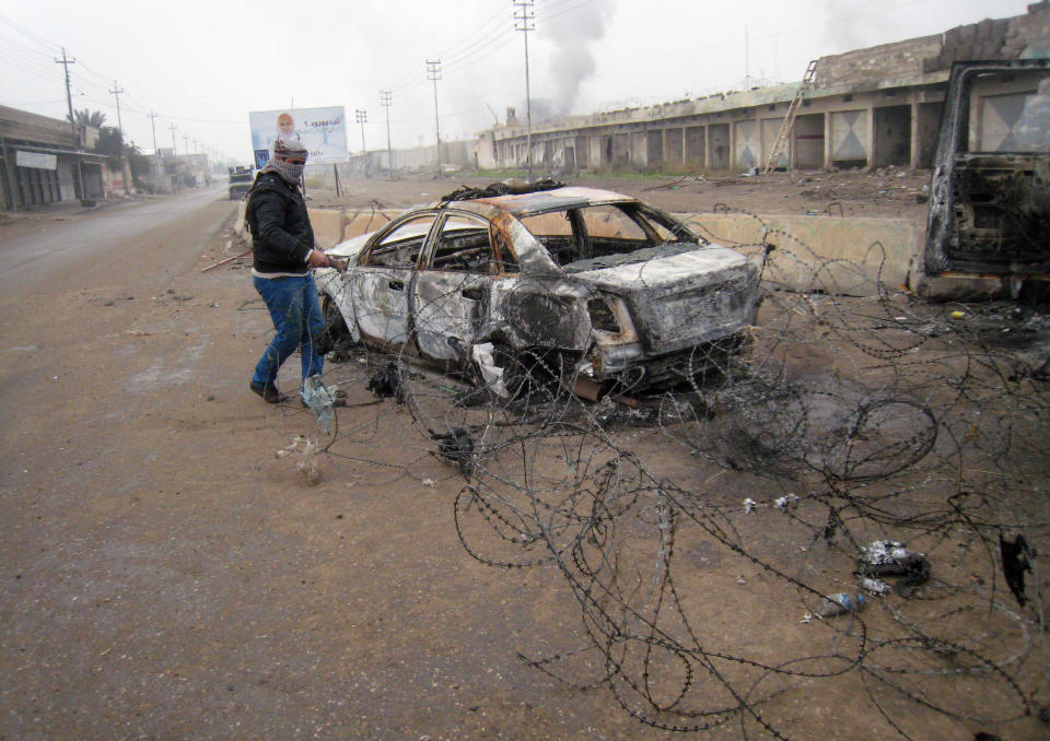 FILE - In this Friday, Jan. 10, 2014 file photo, a masked anti-government gunman clears debris after clashes in Fallujah, Iraq. Islamic militants who took over the Iraqi city of Fallujah are now trying to show they can run it, providing social services, policing the streets and implementing Shariah rulings in a bid to win the support of its Sunni Muslim population. (AP Photo, File)