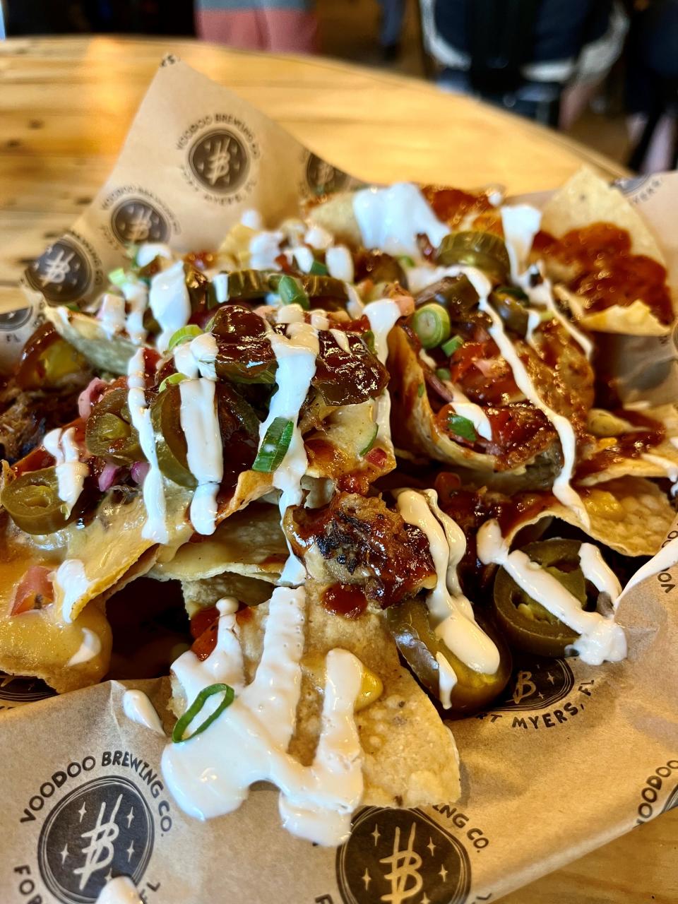 Voodoo's signature nachos come with fresh fried corn tortilla chips, Good Vibes beer cheese, BBQ, lime crema, jalapeños, cilantro, and house pico.