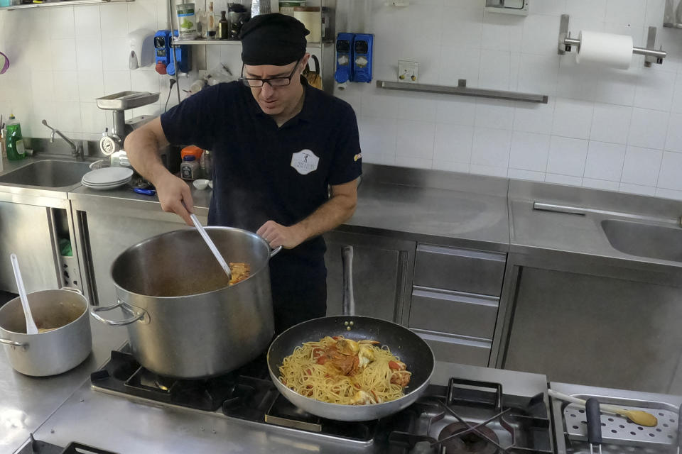 Pasta with blue crabs is prepared at a restaurant kitchen in Orbetello, Italy, Monday, Aug. 14, 2023. If fishing is for now the only way to stop these hordes of blue crabs that are spreading along the coasts of all Italian regions, restaurant kitchens have begun to change their menus, introducing linguine with blue crab or grilled blue crab alongside the more traditional dishes. (AP Photo/Luigi Navarra)