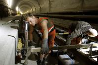 A worker uses a measuring gauge during the installation of the railway tracks in the NEAT Gotthard Base tunnel near Erstfeld May 7, 2012. Crossing the Alps, the world's longest train tunnel should become operational at the end of 2016. The project consists of two parallel single track tunnels, each of a length of 57 km.