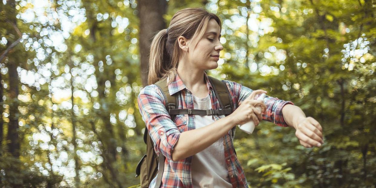 woman applying insect repellent against mosquito and tick during hike in nature skin protection against insect bite