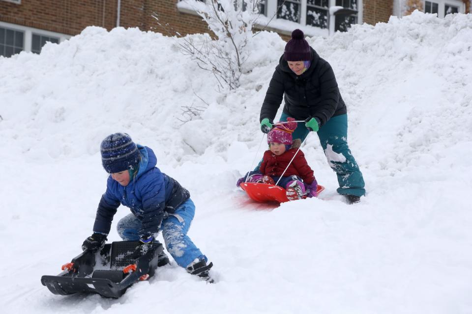 Oliver Hooley, 6, left, climbs onto his sled as Emily Hooley helps Sophia Hooley, 4, onto hers Wednesday, Jan. 10, 2024 at Longfellow Elementary School in Iowa City, Iowa.