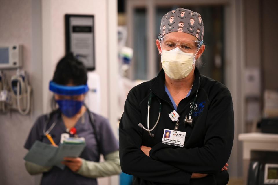 masked doctor, looking down, arms crossed