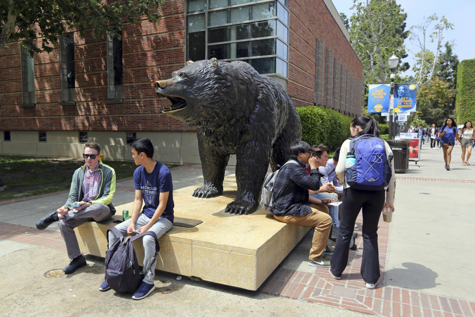 FILE - People stand next to the Bruin statue, the UCLA Mascot, Joe Bruin of the University of California, Los Angeles Friday, April 26, 2019. University of California, Los Angeles, officials have ordered all classes to be held remotely due to threats. UCLA took the step Tuesday, Feb. 1, 2022, a day after students returned to in-person instruction and university officials say the move was made out of an abundance of caution. The university has more than 31,000 undergraduate students and 14,000 graduate students. (AP Photo/Reed Saxon, File)