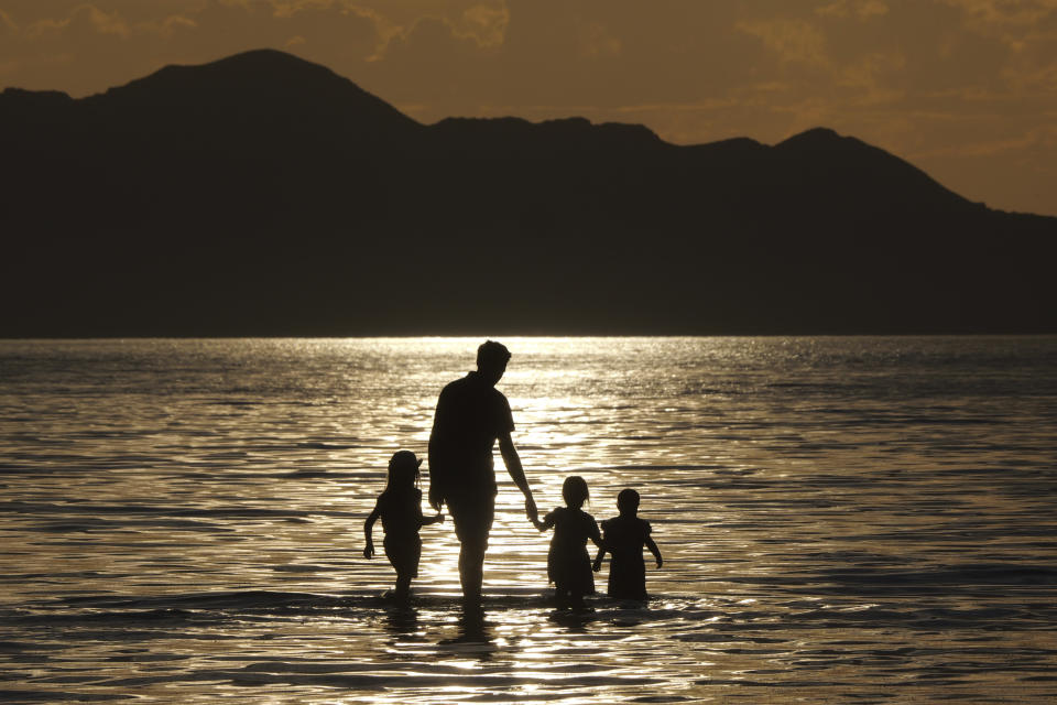 A family walks in the water during sunset at the Great Salt Lake Thursday June 13, 2024, near Salt Lake City. (AP Photo/Rick Bowmer)