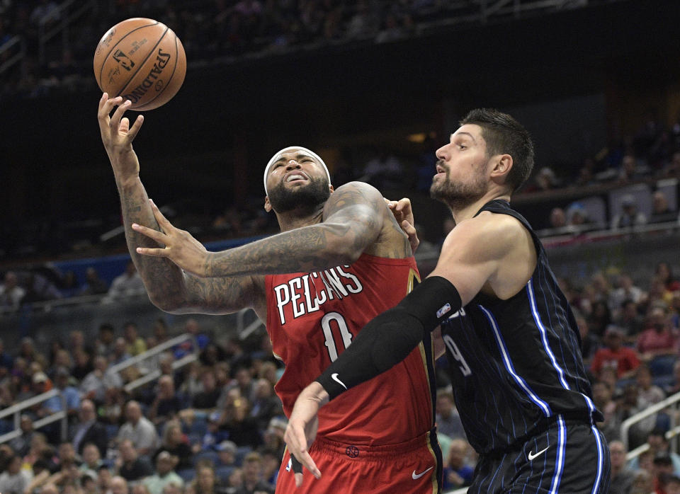 New Orleans Pelicans center DeMarcus Cousins (0) is fouled by Orlando Magic center Nikola Vucevic (9) while going up for a shot during the second half of an NBA basketball game Friday, Dec. 22, 2017, in Orlando, Fla. (AP Photo/Phelan M. Ebenhack)