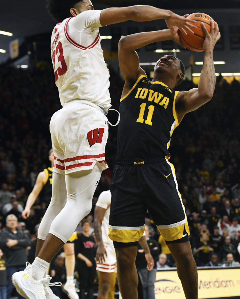 Iowa guard Tony Perkins (11) makes the game winning basket under pressure from Wisconsin guard Chucky Hepburn (23) during overtime in an NCAA college basketball game, Saturday, Feb. 17, 2024, in Iowa City, Iowa. (AP Photo/Cliff Jette)