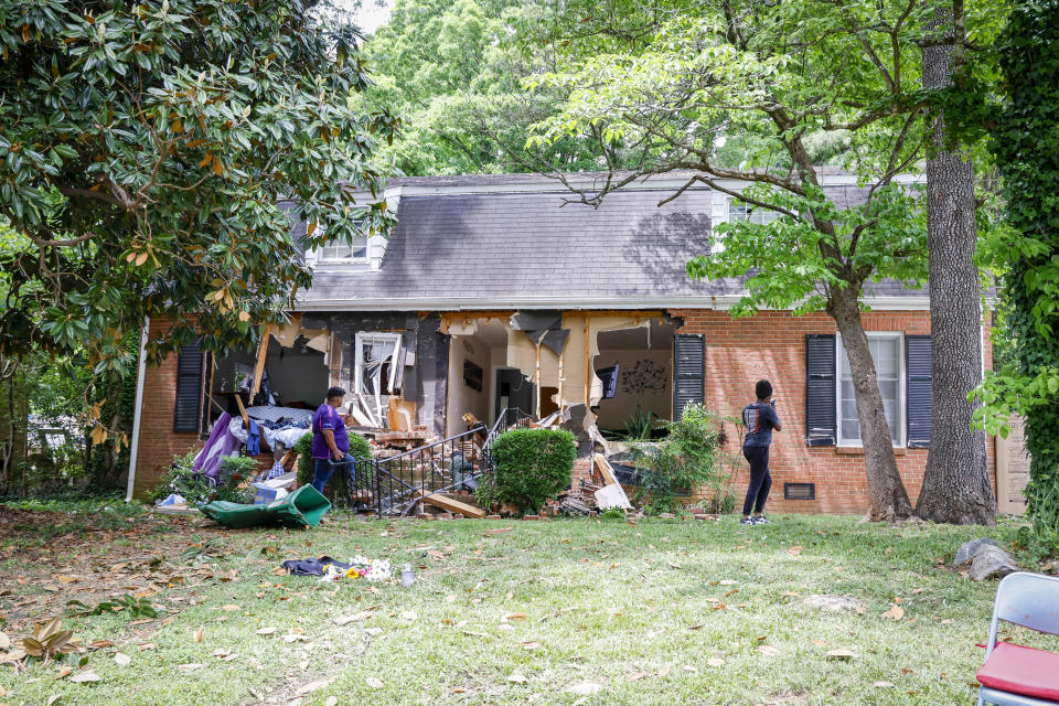 People take photos of a home, Tuesday, April 30, 2024, where a shootout between a suspect and officers occurred on Monday, in Charlotte, N.C. Police say a shootout that killed four law enforcement officers and wounded four others began as officers approached the home to serve a warrant for a felon wanted for possessing a firearm. (AP Photo/Nell Redmond)