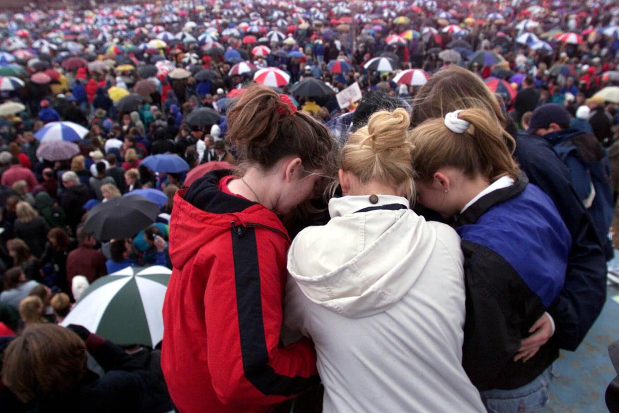 Students hug during the memorial service for victims of the Columbine High School shooting tragedy on April 25, 1999.