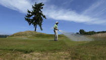 FILE - Bruce Murray, a greenskeeper at Chambers Bay golf course, waters the 16th tee next to the course's signature lone fir tree, Thursday, June 11, 2015, in University Place, Wash., a week before hosting the U.S. Open golf tournament. The sight of fountains, swimming pools, gardens and golf courses in Western cities like Phoenix, Los Angeles, Las Vegas, San Diego and Albuquerque can seem jarring with drought and climate change tightening their grip on the region. But Western water experts say they aren’t necessarily cause for concern. Many Western cities over the past three decades have diversified their water sources, boosted local supplies, and use water more efficiently now than in the past. (AP Photo/Ted S. Warren, File)