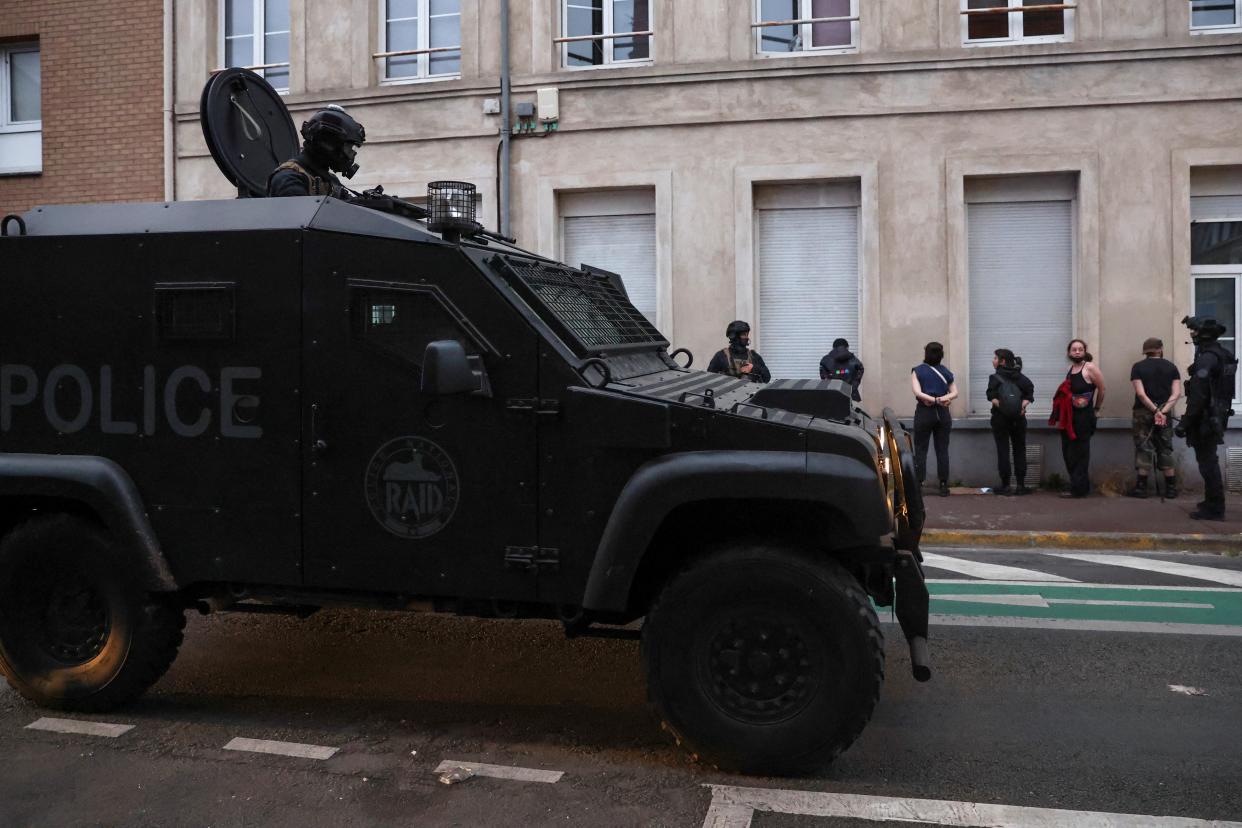 A riot police vehicle passes by a group of detained demonstrators in Lille (REUTERS)