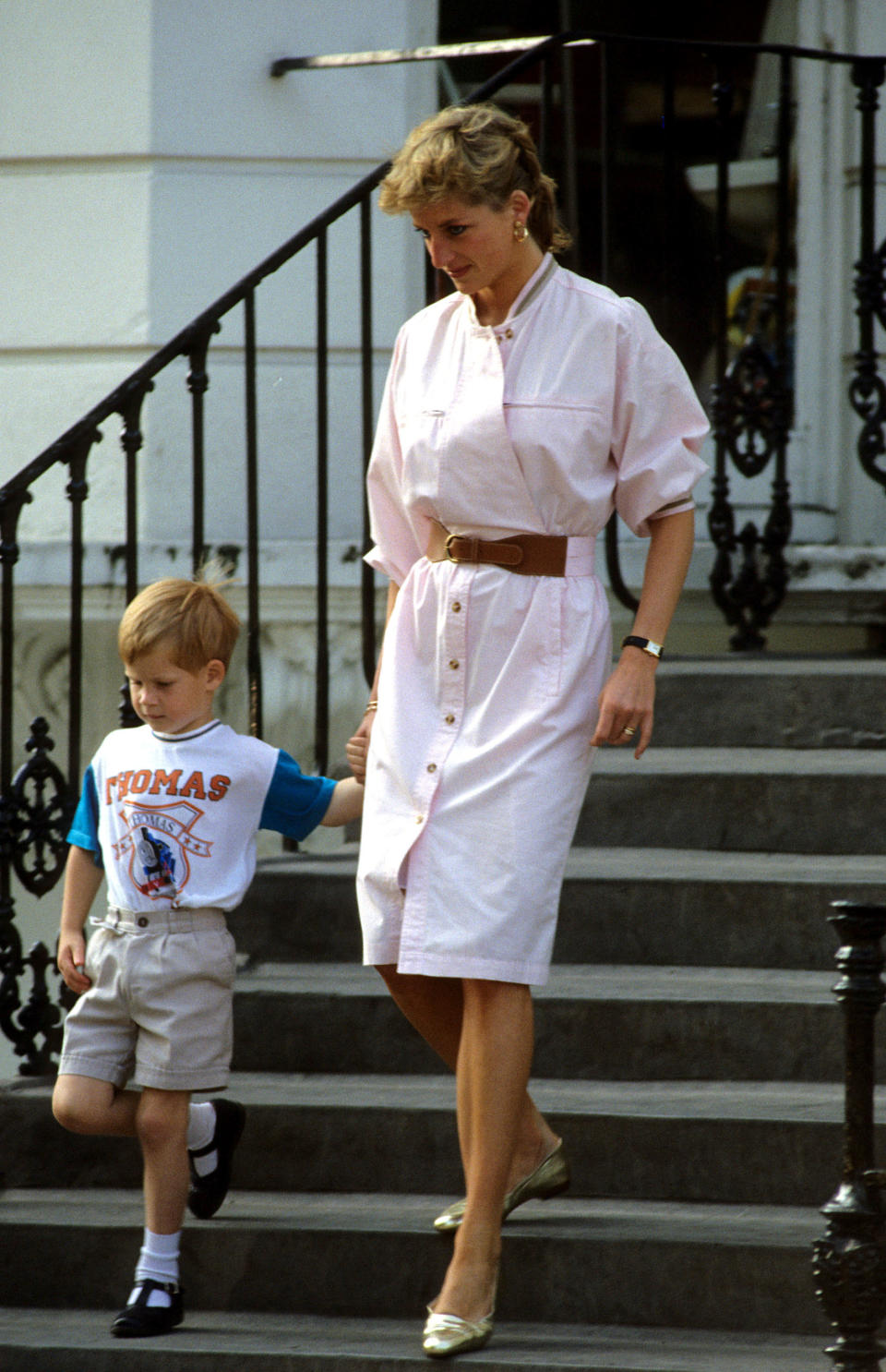 Prince Harry wears a Thomas the Tank Engine t-shirt when he leaves nursery school with his mother Diana, Princess of Wales in June 1989 in London.