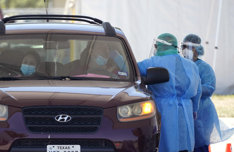 Medical personnel administer COVID-19 testing at a drive-through site, Friday, Aug. 14, 2020, in San Antonio. Coronavirus testing in Texas has dropped significantly, mirroring nationwide trends, just as schools reopen and football teams charge ahead with plans to play. (AP Photo/Eric Gay)