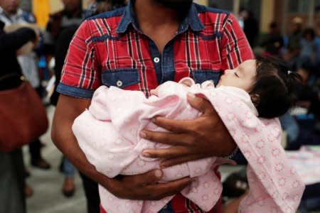 FILE PHOTO: A Honduran migrant, part of a caravan trying to reach the U.S., carries his daughter at a migrant shelter in Guatemala City, Guatemala October 17, 2018. REUTERS/Luis Echeverria/File Photo