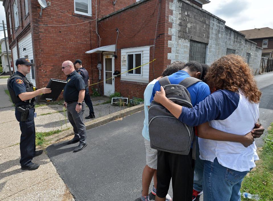 Mourners, at right, pray on Aug. 29, 2018, near the scene of the fatal shooting of Calvin Isaiah, 24, on East 26th Street. He was shot earlier that day.