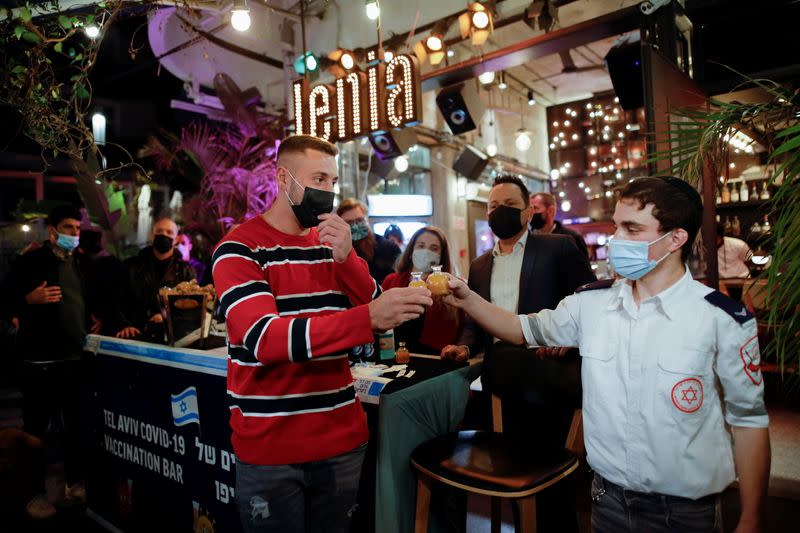 A man and a medical worker toast drinks at a bar where residents who got a vaccination against the coronavirus disease (COVID-19) received a free drink as part of an initiative by Tel Aviv municipality to encourage residents to get vaccinated, in Tel Aviv