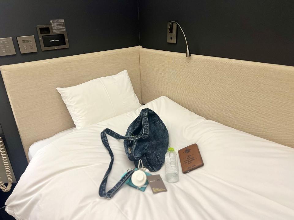 The author's blue purse, a water bottle, and the author's passport on the white bedspread.