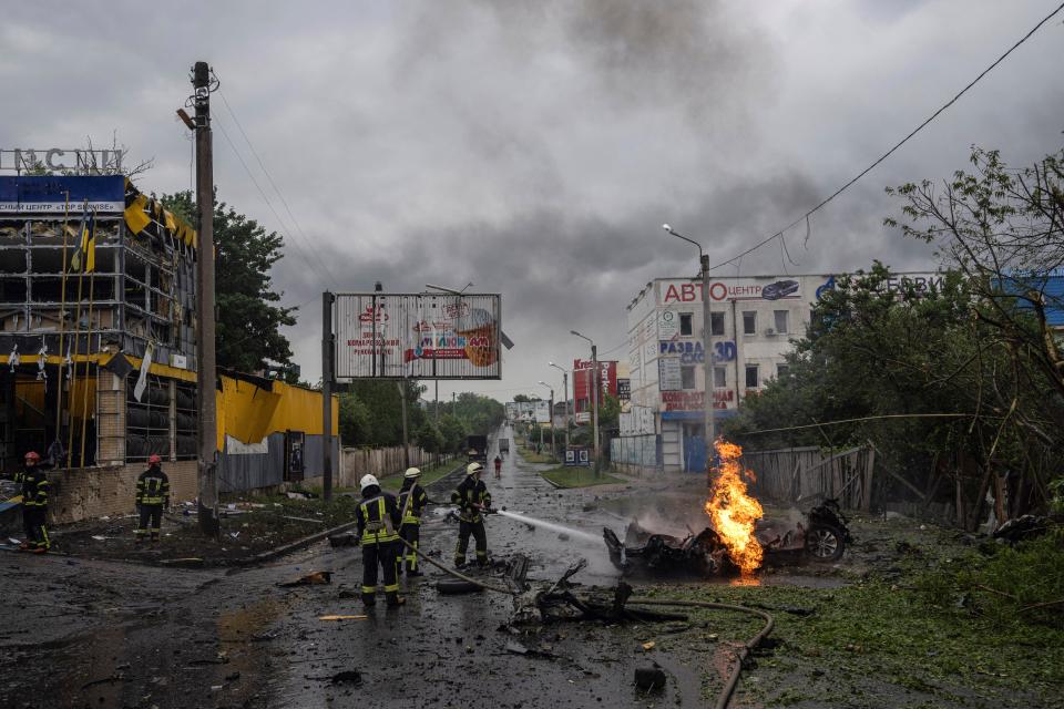 Rescue workers put out the fire of a destroyed car after a Russian attack in a residential neighbourhood in downtown Kharkiv (AP Photo/Evgeniy Maloletka)