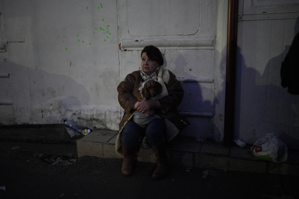 A refugee holding her dog sits by the side of the road approaching the border with Poland in Shehyni, Ukraine, Sunday, March 6, 2022. (AP Photo/Daniel Cole)