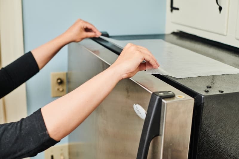 placing a piece of wax paper on top of the refrigerator