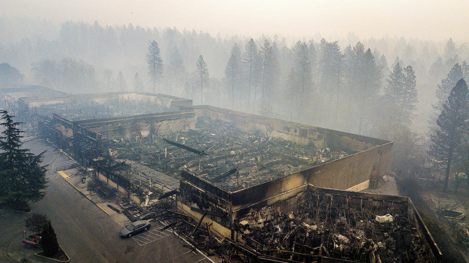 FILE - In this Thursday, Nov. 15, 2018 file photo smoke hangs over the scorched remains of Old Town Plaza following the wildfire in Paradise, Calif. Authorities say the fire is 95 percent contained Thursday, Nov. 22. The deadly blaze that started Nov. 8 leveled Paradise, killing multiple people and destroyed thousands of homes. (AP Photo/Noah Berger, File)